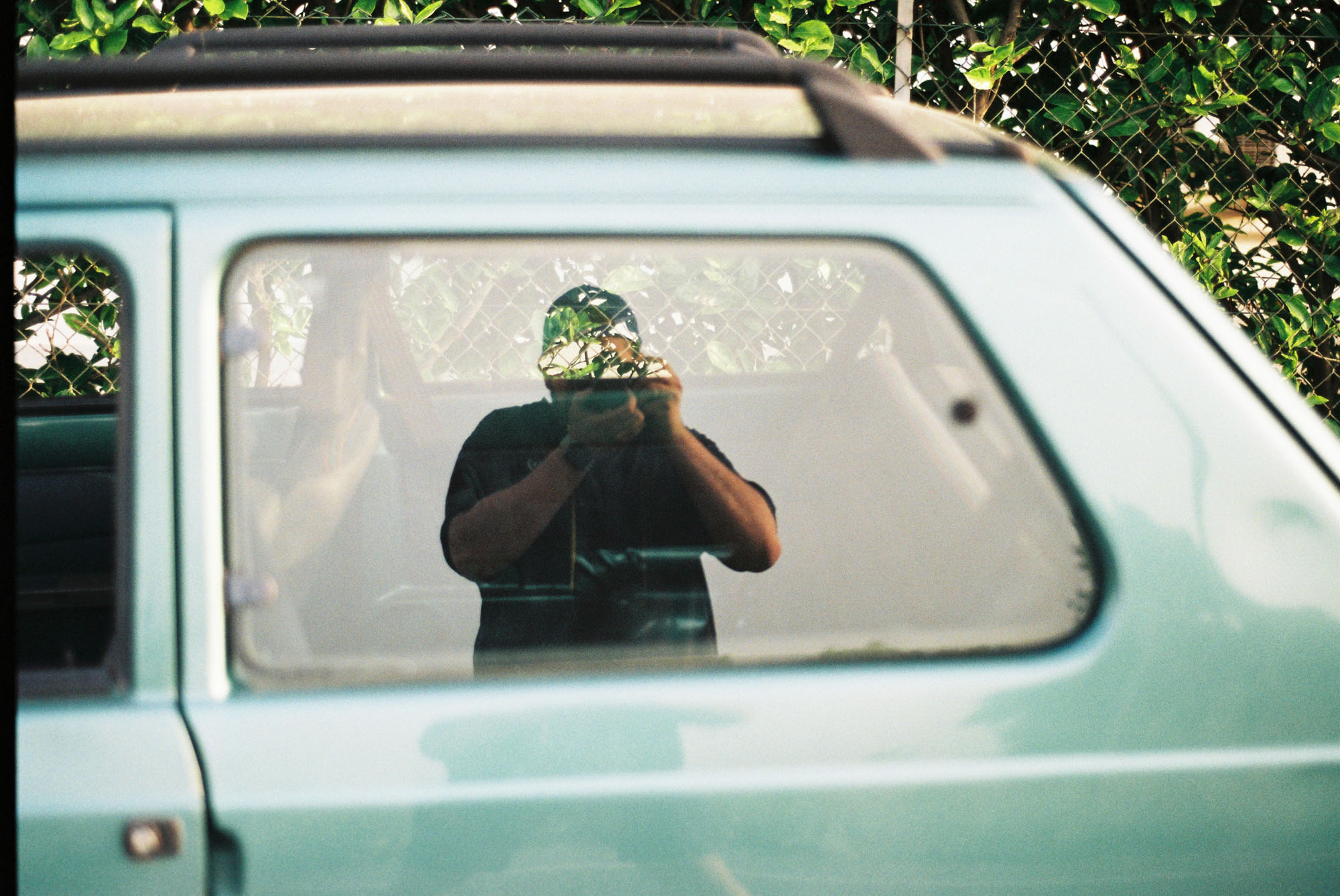 Simone reflected in a car window with a camera