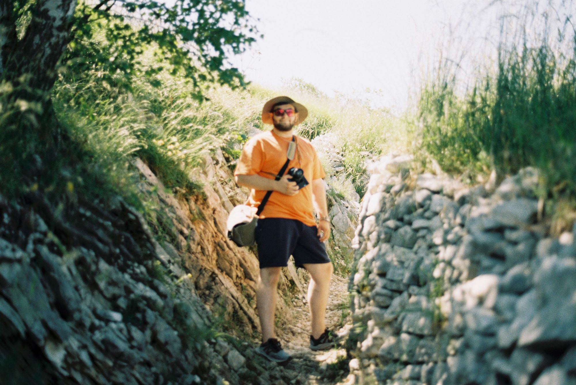 Simone walking on a mountain path with a camera